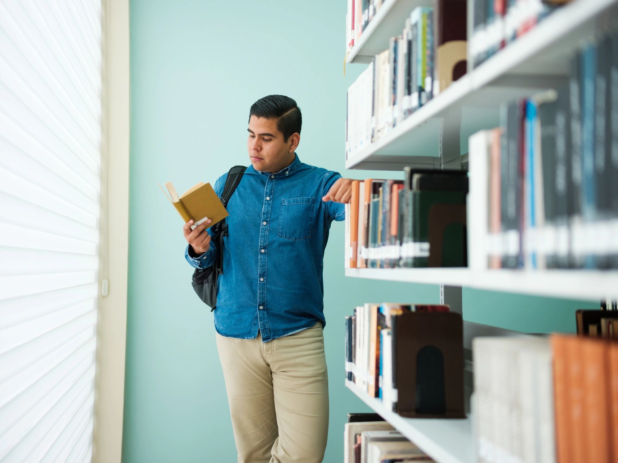 Student reading in a library representing learning development