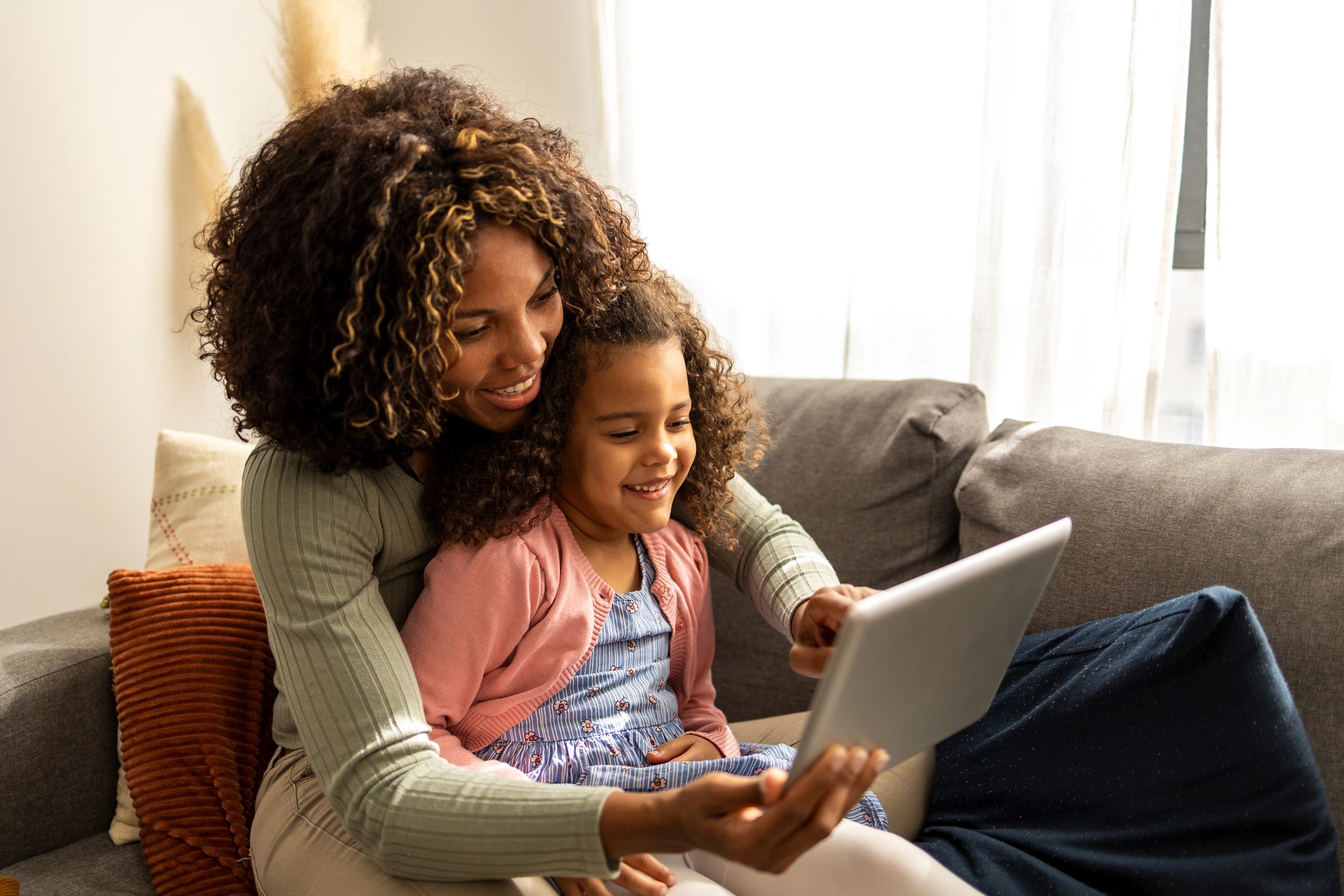 Mother and daughter using a digital tablet together in the living room