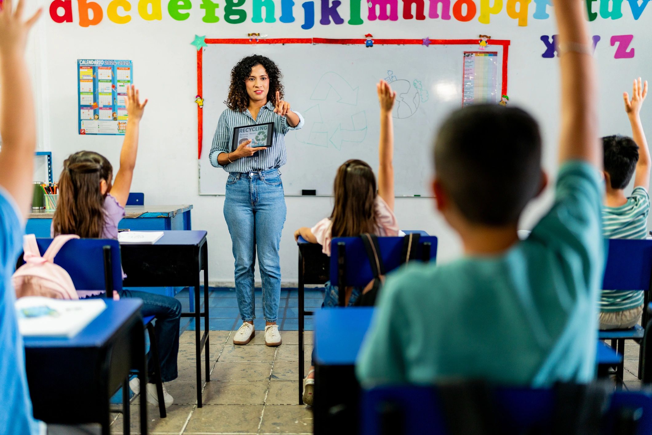 Young teacher woman talking to child students during class at school